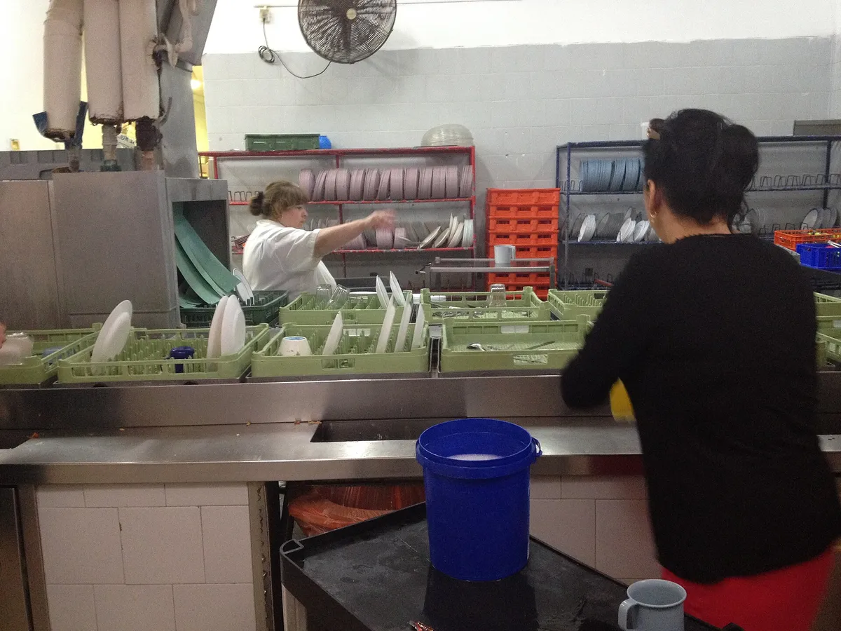 A commercial dish room with stainless tables and dish racks, part of a restaurant kitchen deep cleaning scope