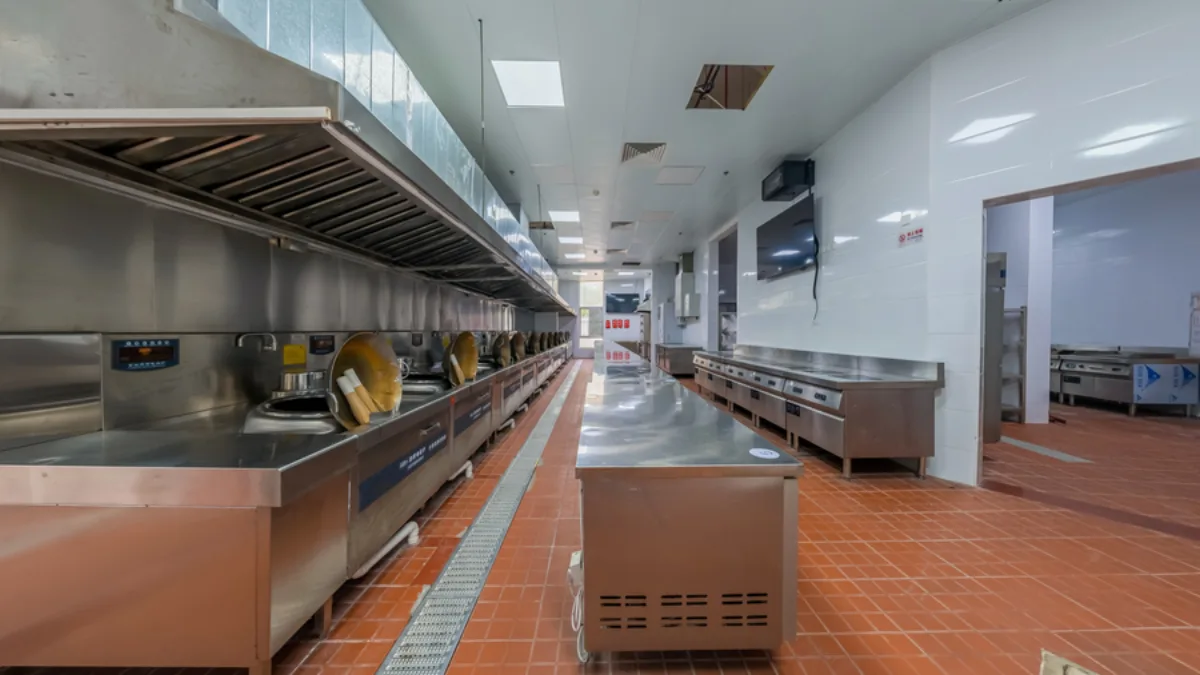 Large clean commercial kitchen with overhead exhaust canopy system and stainless cooking line